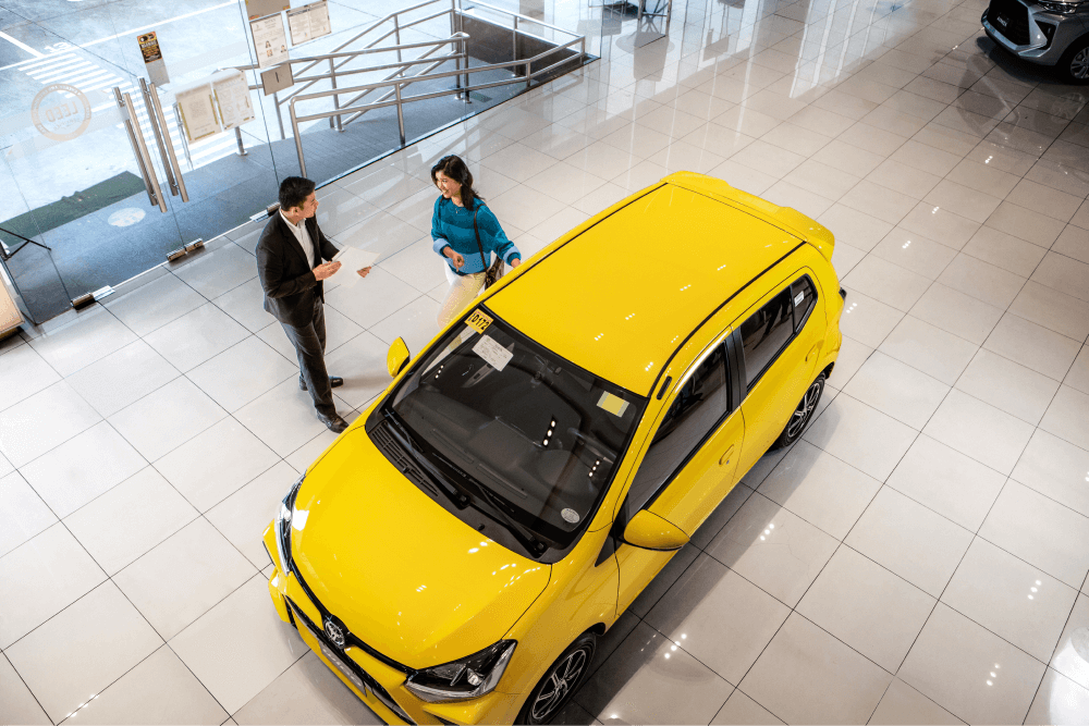 woman and agent next to a yellow toyota wigo